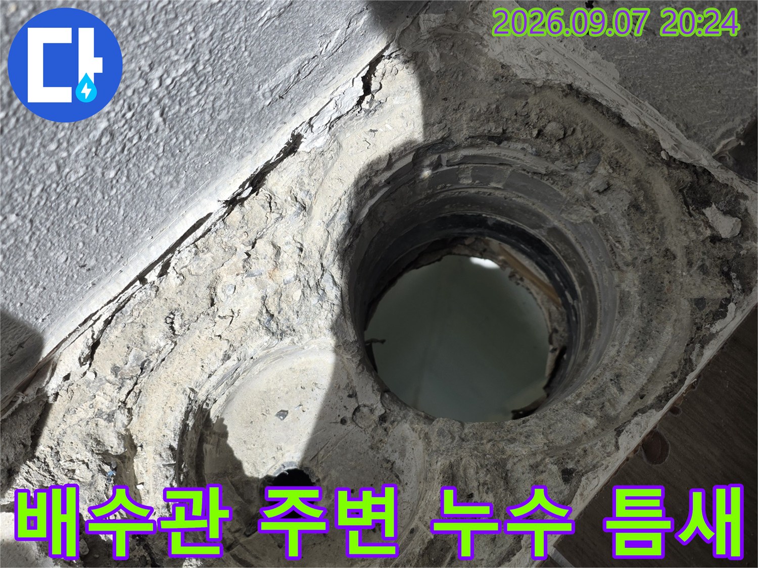 하수구 배관 주위의 부실한 방수층과 오염된 마감 상태를 보여줍니다.