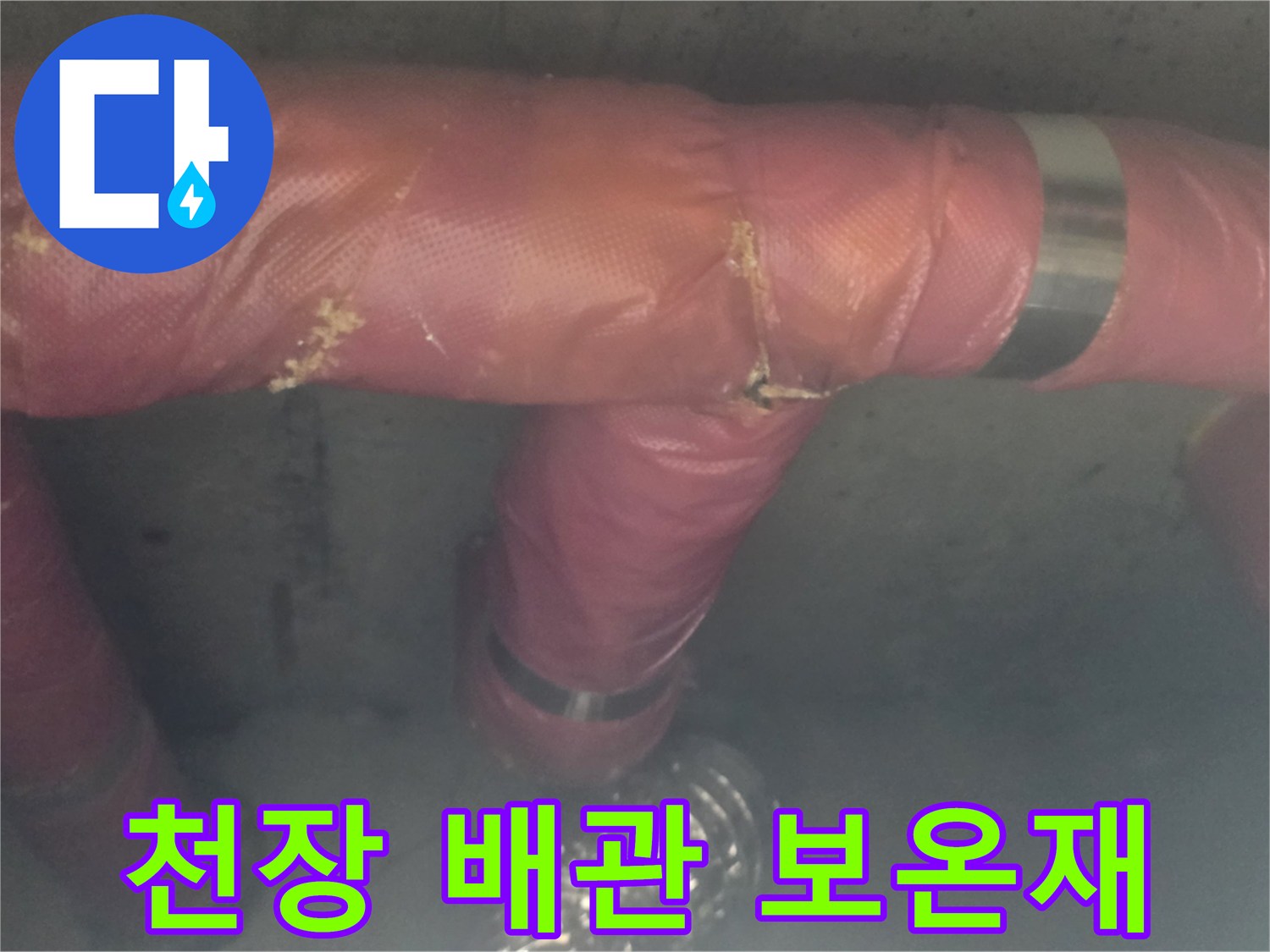 손상된 분홍색 보온재가 씌워진 천장 내부 배관
