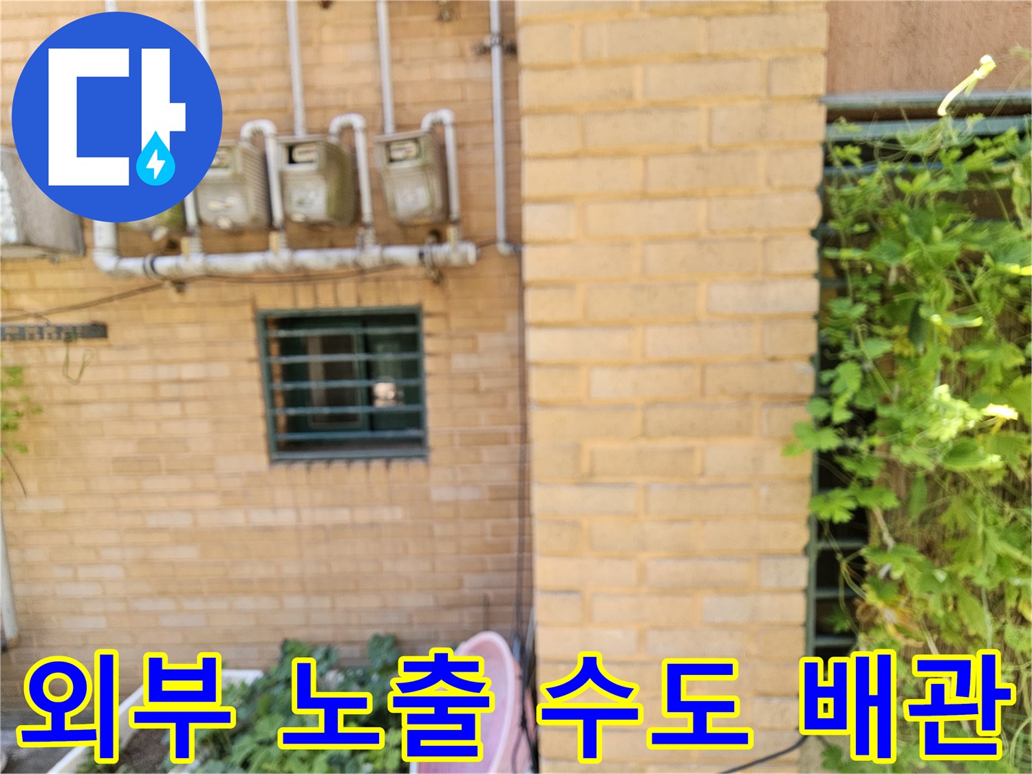 벽돌 벽면에 설치된 수도 계량기와 여러 개의 수직 배관 모습
