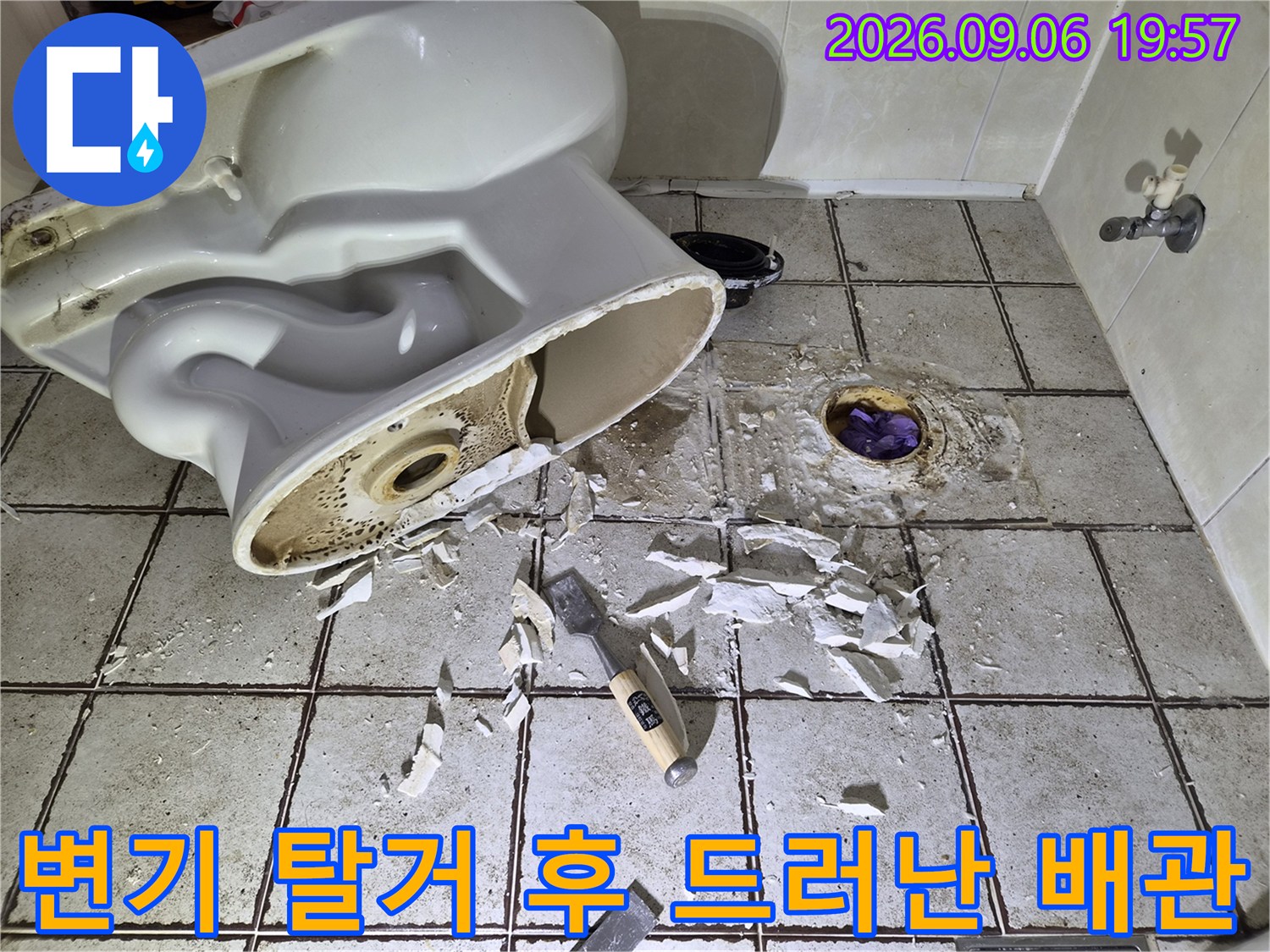 양변기를 들어낸 뒤 노출된 오수관과 주변 타일의 상태입니다.