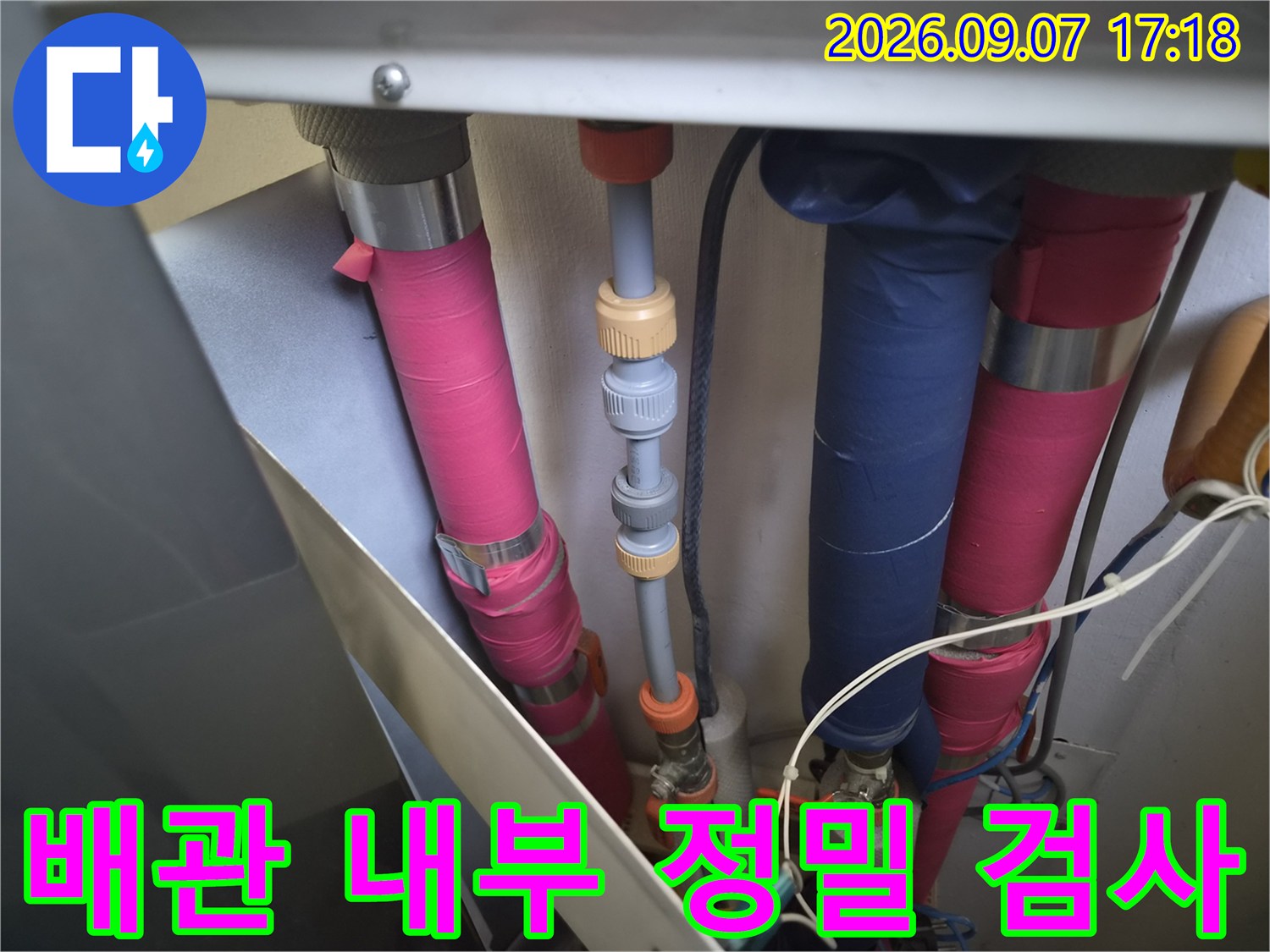 분홍색 배관과 파란색 덮개가 있는 복잡한 구조의 배관 연결 부위를 집중적으로 관찰하고 있습니다.