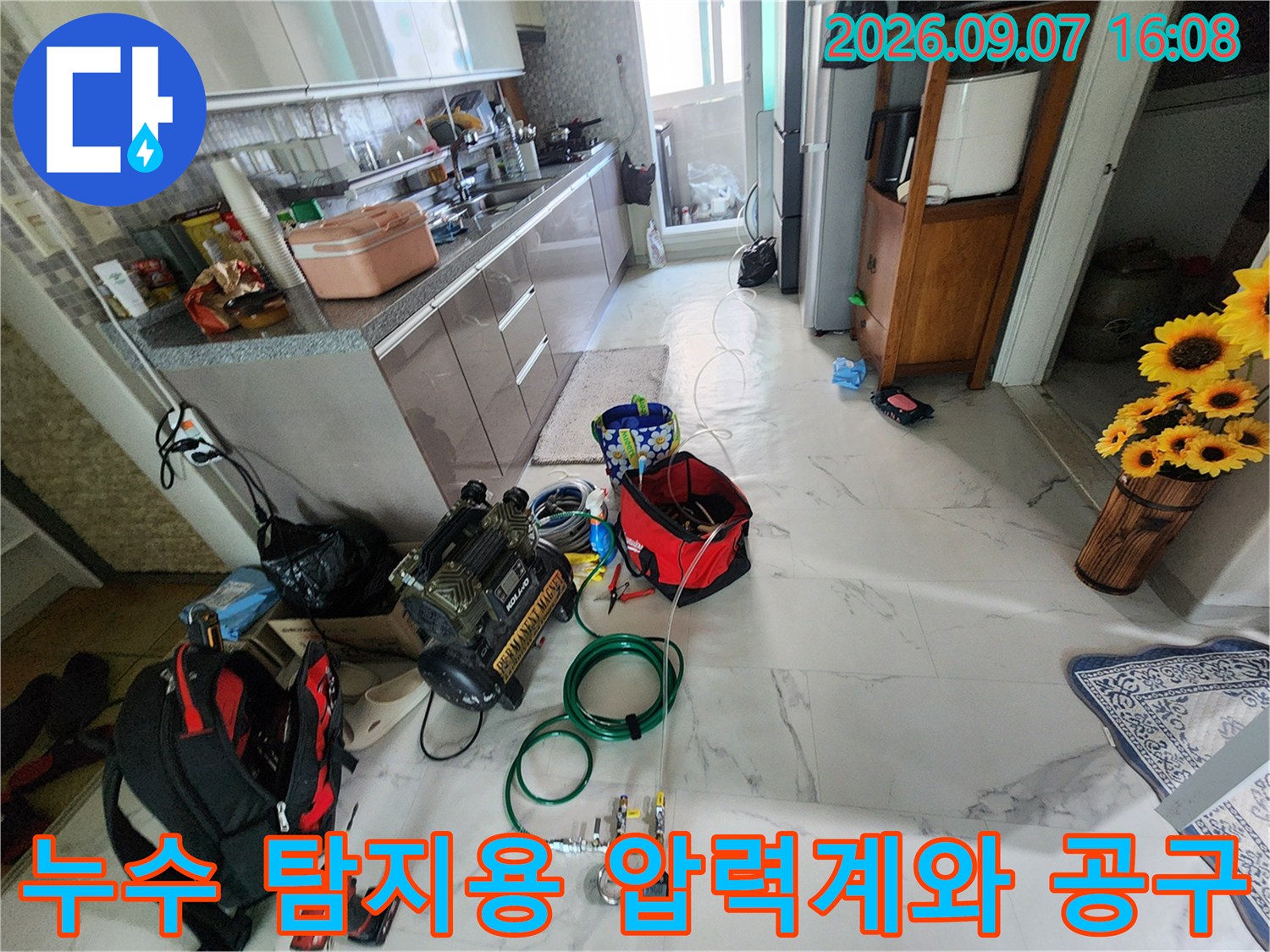 싱크대 하부 작업 공간에 배치된-배관 압력 측정 장비와 전문 공구들