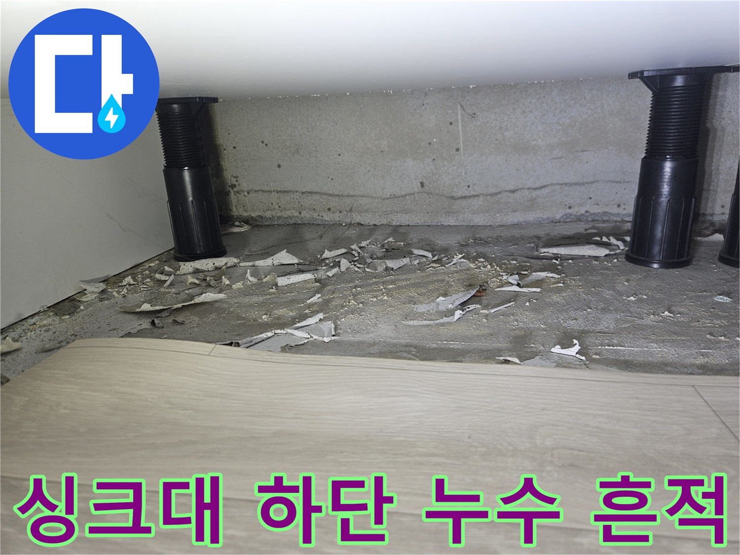 싱크대 배관 주변 콘크리트의 젖은 부위와 파손된 마감재