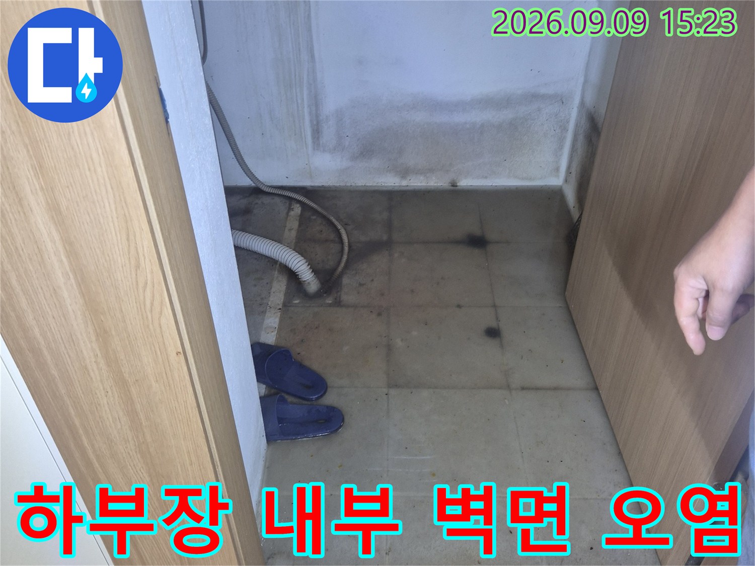싱크대 아래쪽 공간의 습기 찬 벽면과 변색된 타일 부위