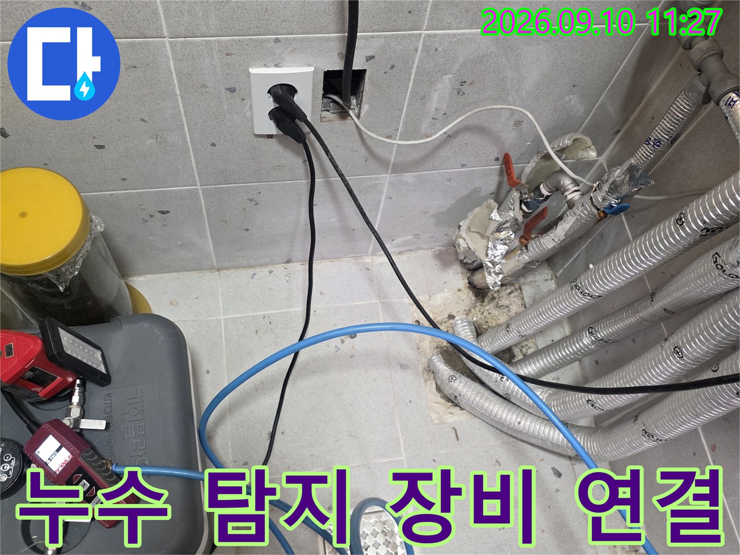 배관에 압력을 걸기 위해 연결된 파란색 호스와 측정 장비입니다.