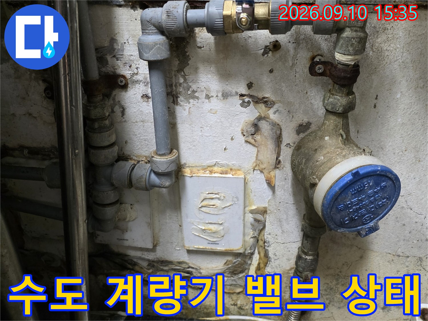파란색 캡의 수도 계량기와 물기가 남아있는 노후 배관의 모습입니다.