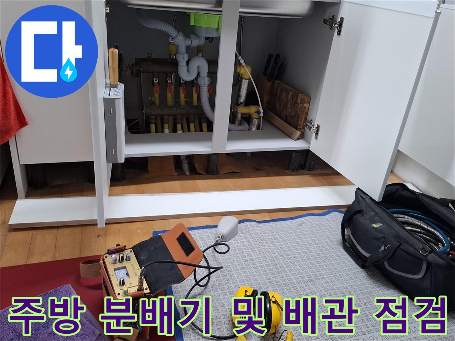 싱크대 하부장 내부의 노란색 난방 배관과 분배기 연결 구조