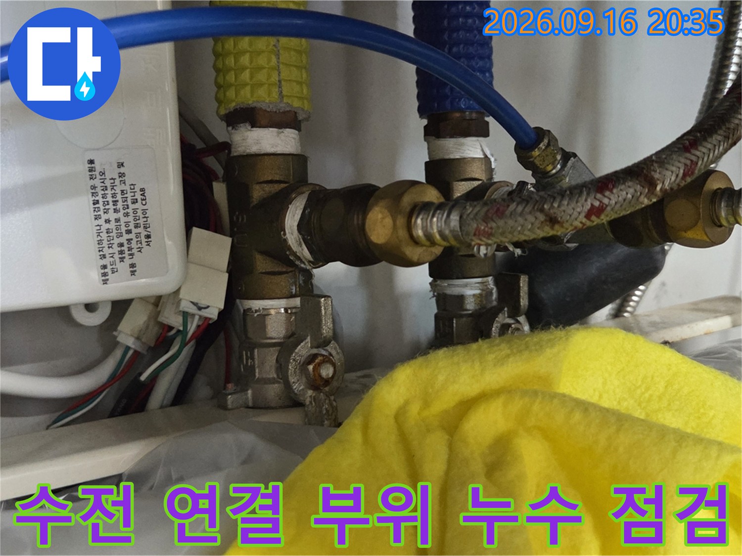 금속 배관과 파란색 호스 사이의 수전 연결 상태를 정밀하게 검사하고 있습니다.